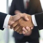 Dos profesionales estrechándose la mano durante una reunión